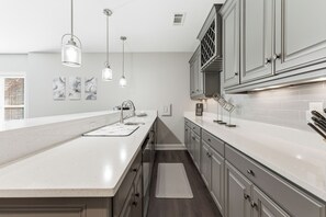A modern kitchen with a large island, pendant lights, and a backsplash.