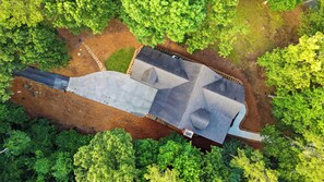 An aerial view of a building with a flat roof, surrounded by dense green trees.