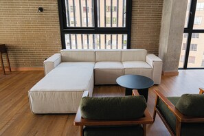 Una sala moderna con un sofá modular, una mesa de centro redonda y dos sillones.