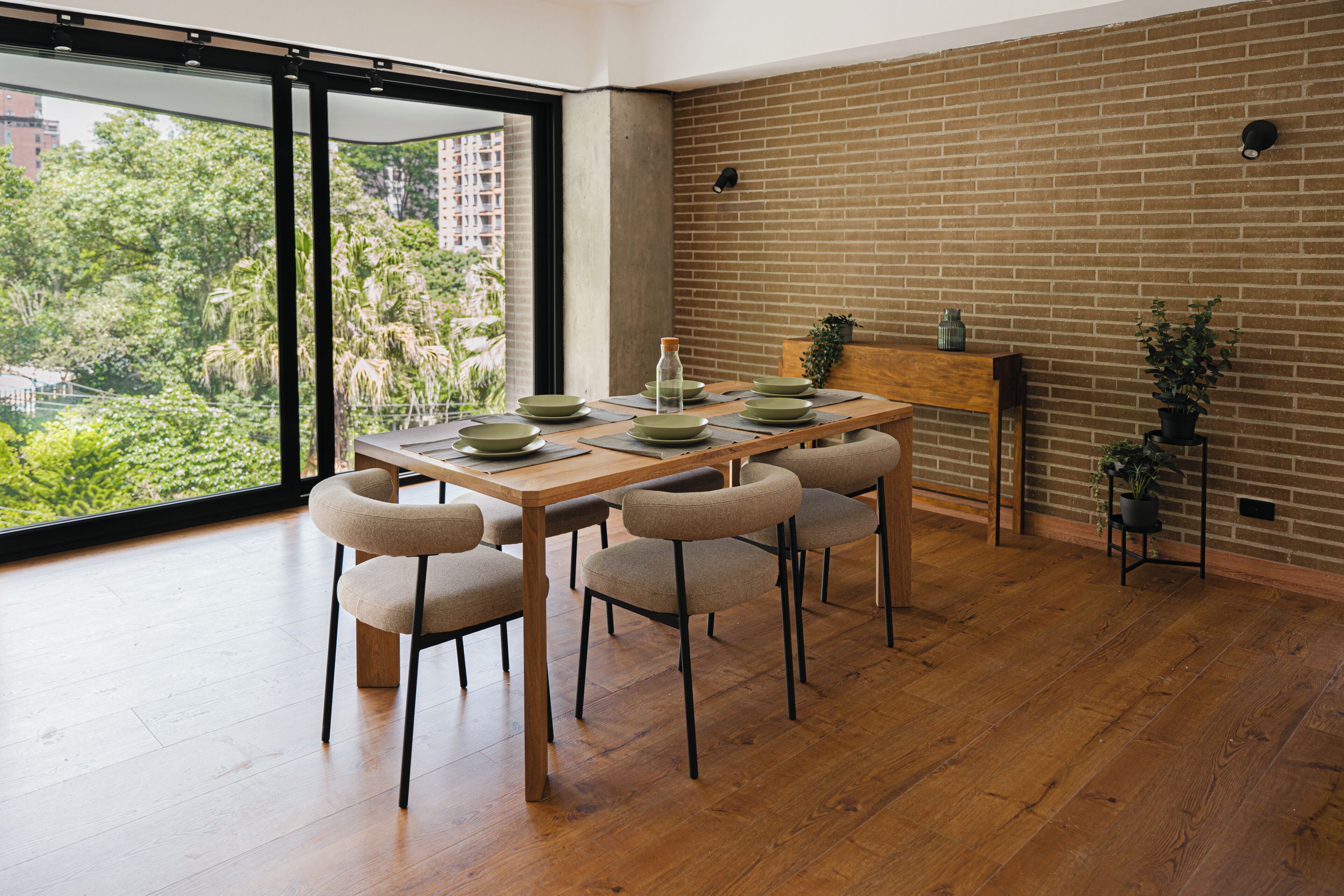 A dining area with a wooden table, four chairs, and a brick wall.