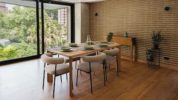 A dining area with a wooden table, four chairs, and a brick wall.
