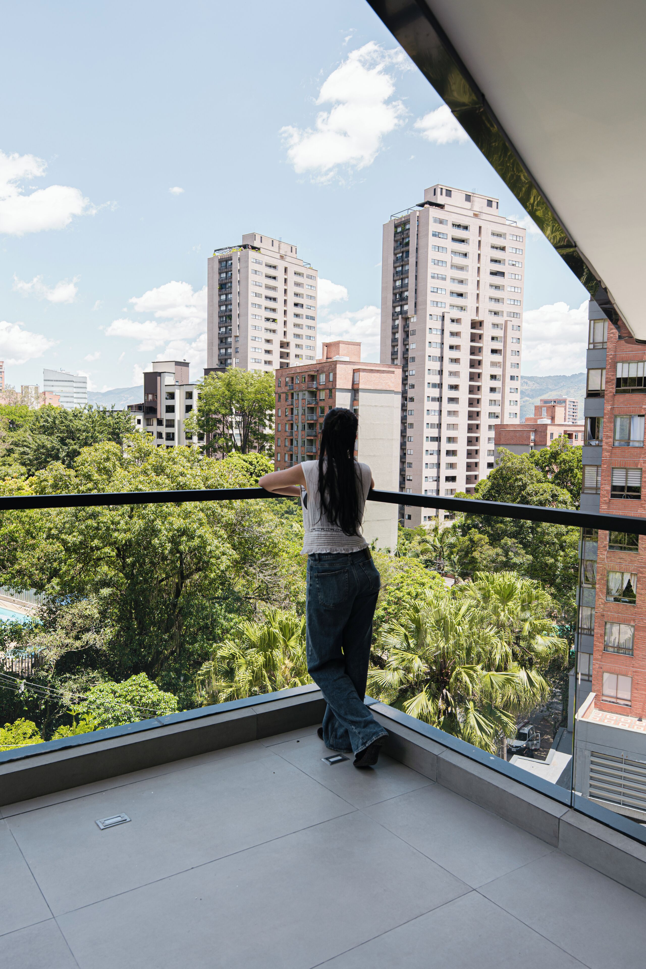 Uma varanda com vista para a paisagem urbana, incluindo edifícios altos e áreas verdes.