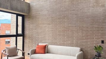 Een moderne woonkamer met een bakstenen muur, een bank, een fauteuil, een salontafel en hanglampen.
