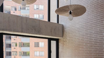 Een modern interieur met een groot raam, een bank, een bijzettafeltje met een plant en hangende lampen.