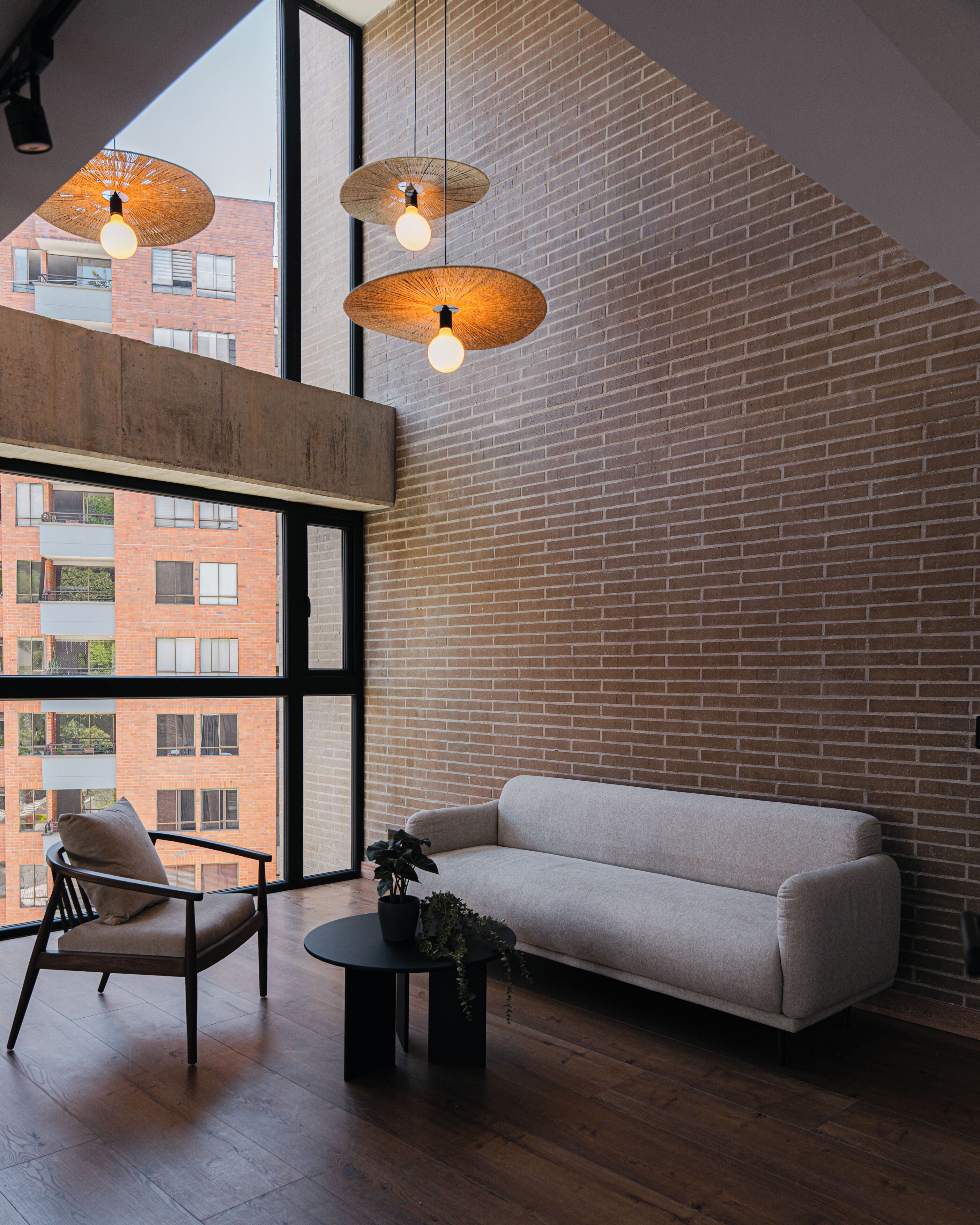 Un intérieur moderne avec un mur en briques, un canapé, un fauteuil et une petite table sur laquelle est posée une plante.