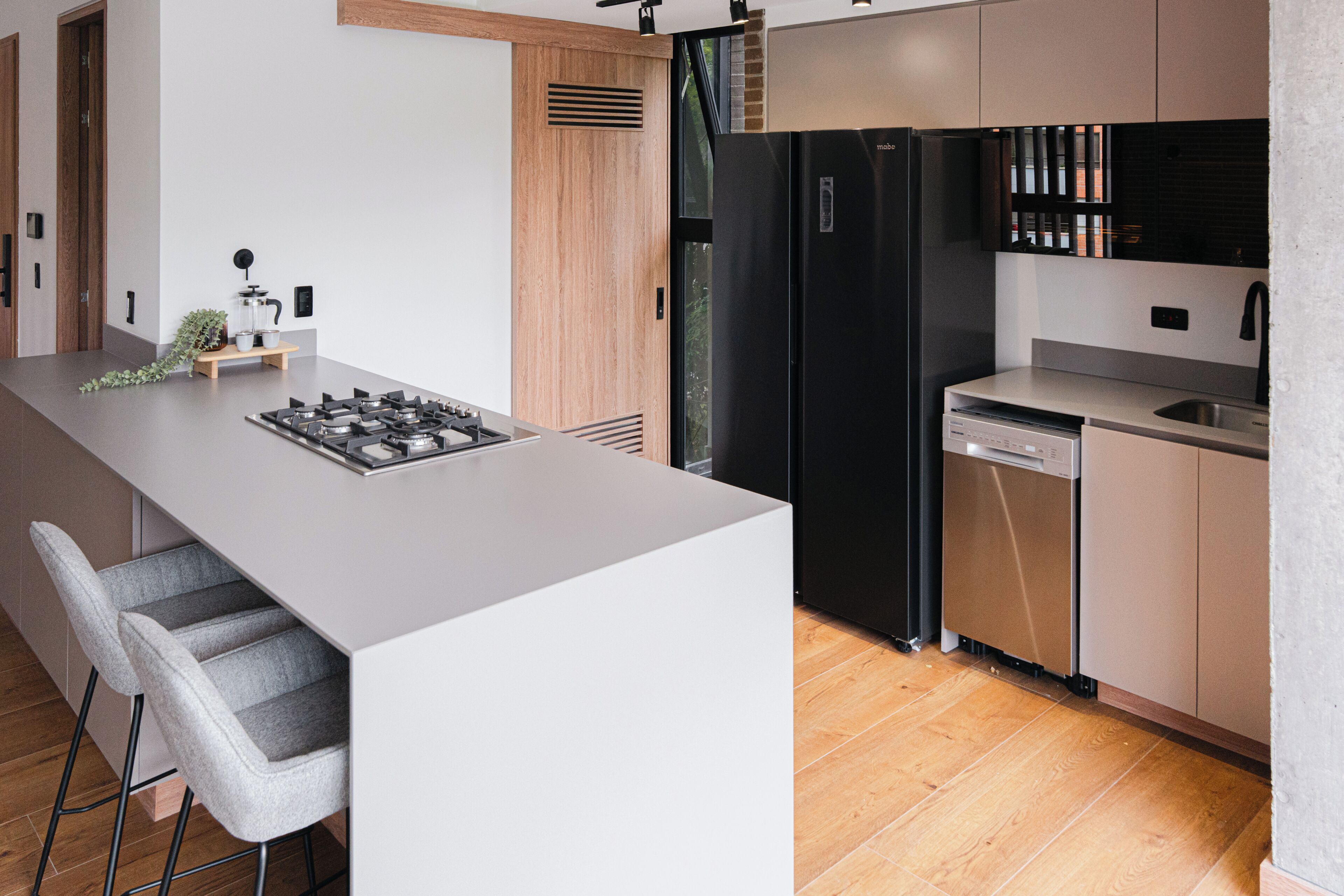 A modern kitchen with a central island, stainless steel appliances, and a wooden floor.