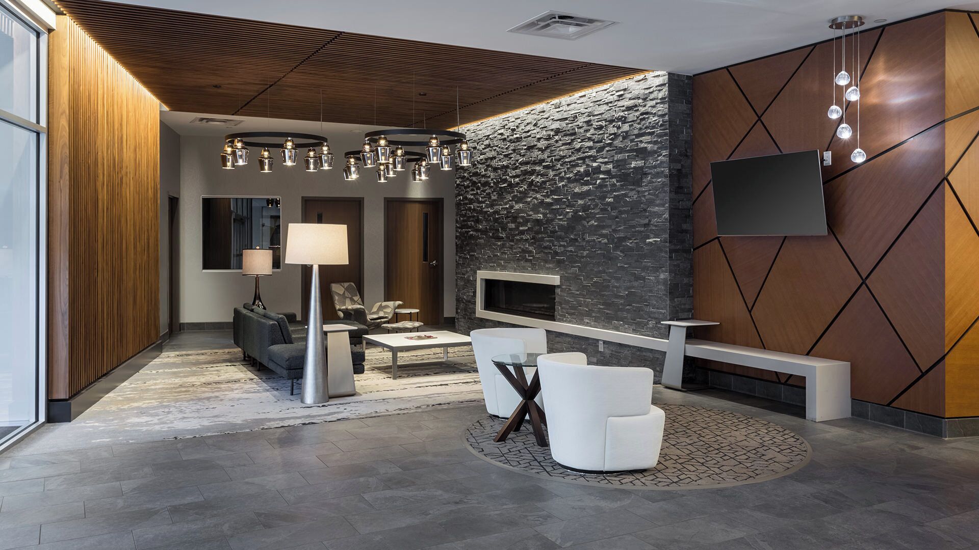 A modern interior with a stone wall, a fireplace, and a flat-screen TV mounted on the wall.