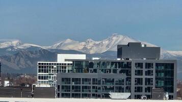 A modern building with multiple floors and large windows, set against a backdrop of snow-capped mountains.