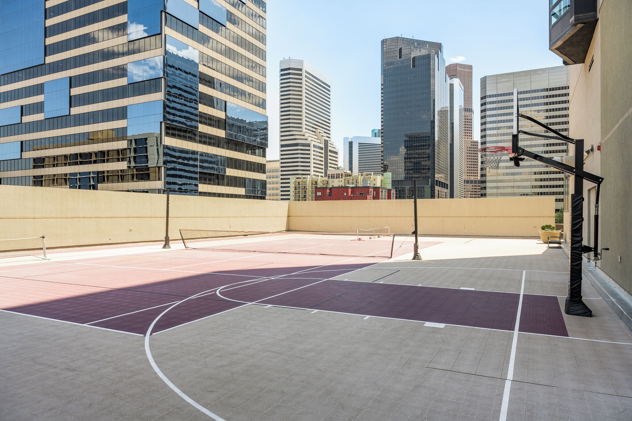 An outdoor basketball court with a net, surrounded by buildings.