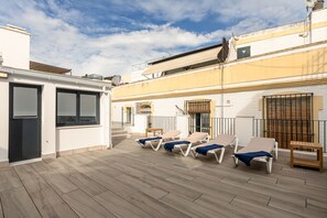 Une terrasse sur le toit, avec des chaises longues et une petite table.