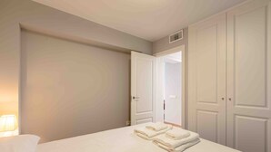 Une chambre d’hôtel avec un lit, une table de chevet, une lampe et une armoire.