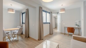 Une chambre d’hôtel moderne dotée d’un coin repas, d’un espace détente et d’un espace de travail.