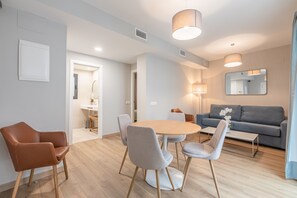 Ein modernes Wohnzimmer mit rundem Tisch, Stühlen, einer Couch und einem großen Spiegel.