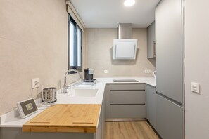 Eine kleine Küche mit Holzarbeitsplatte, integriertem Spülbecken, einer Kaffeemaschine und einem kleinen Fenster.