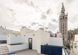 A rooftop terrace with a pool, a door, and a view of a historic tower. - B0 Apartment with Cathedral Views – Historic Center of Seville and Pool (Seville)