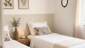 Ein Schlafzimmer mit zwei Betten, einem Nachttisch mit Lampe und einer Wand-Klimaanlage.
