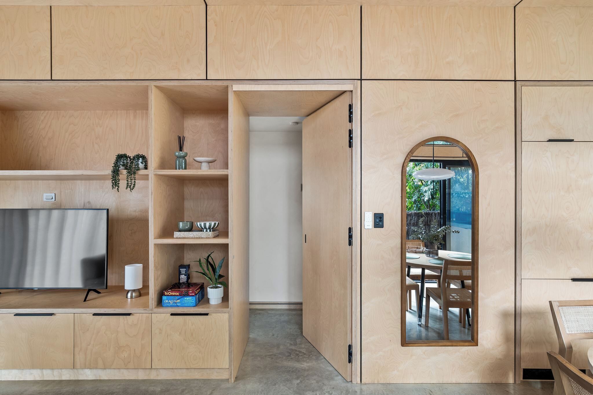 A modern kitchen with built-in cabinets, a flat-screen TV, and a dining area with a table and chairs.