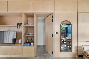 A modern kitchen with built-in cabinets, a flat-screen TV, and a dining area with a table and chairs. - House Kayu - A unique home in the heart of Margaret River (Margaret River)