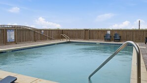 Piscina rectangular con cerca de madera y un cartel que indica las normas de la piscina y la prohibición de clavados.
