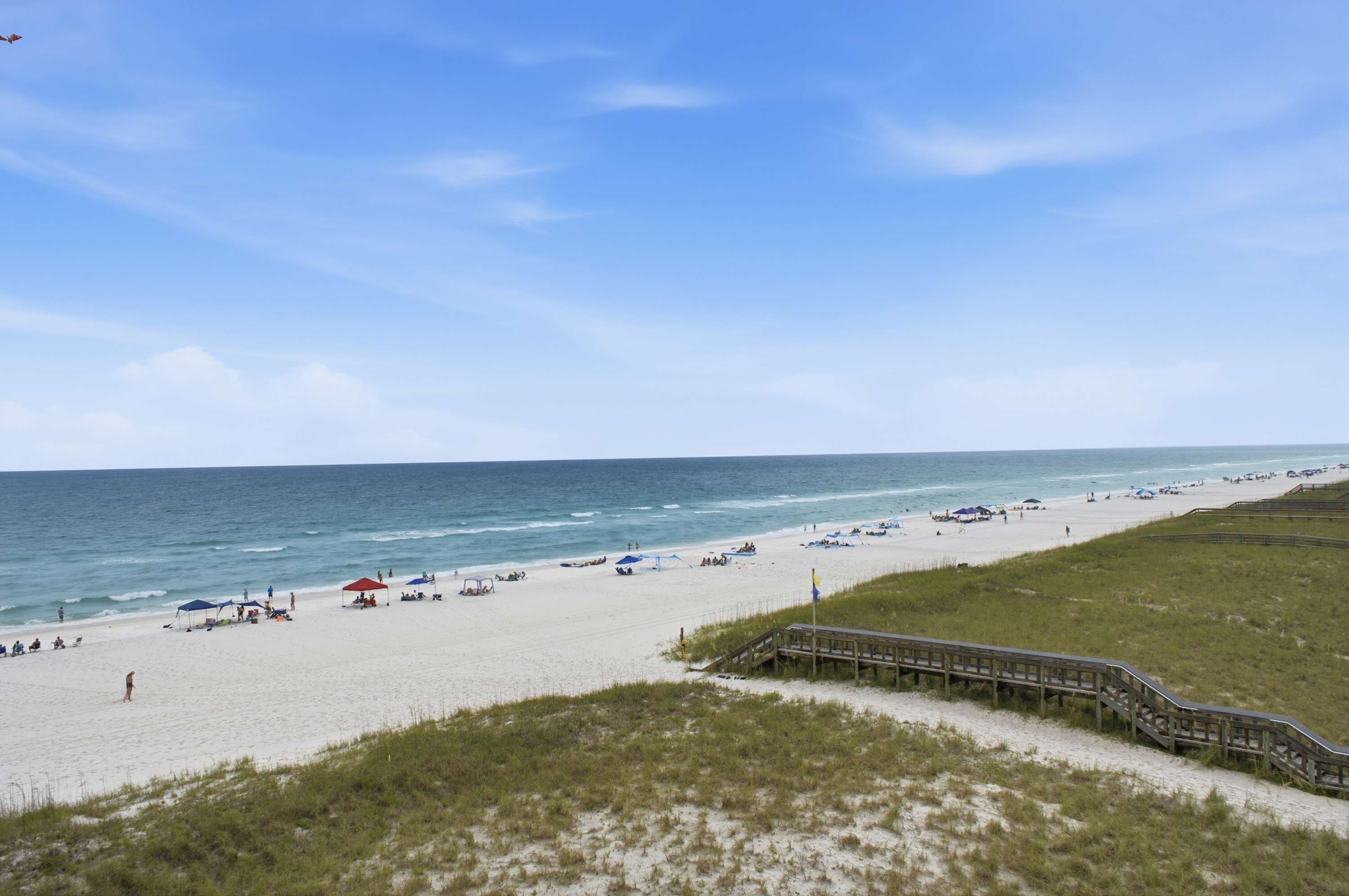 A beach with a wooden boardwalk leading to the shore, sandy beach, and the ocean.