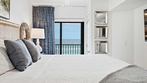 Habitación de hotel con una cama grande, vistas al mar y un balcón.