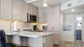 Una cocina con una isla central, electrodomésticos de acero inoxidable y un microondas sobre la encimera.