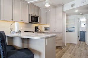 A kitchen with a central island, stainless steel appliances, and a microwave above the counter. - Gulf Front • Pool • Beach Access • Sundunes 144 (Navarre)