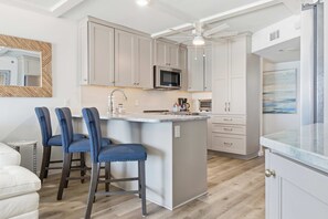 Een moderne keuken met een centraal eiland, barkrukken en een plafondventilator.