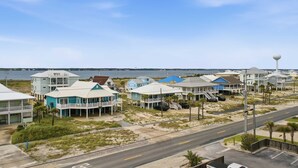 Una zona residencial costera con propiedades frente al mar, una carretera y una masa de agua al fondo.
