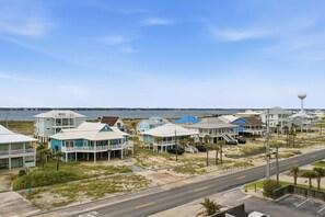 A coastal residential area with beachfront properties, a road, and a water body in the background. - Gulf Front • Pool • Beach Access • Sundunes 144 (Navarre)