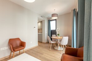 A modern living room with a dining area, featuring leather chairs, a round table, and a large window with curtains. - A2 Apartment with Cathedral Views – Historic Center of Seville and Pool (Seville)