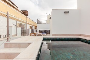 Ein Poolbereich mit Glasumrandung, einer Liege und einem kleinen Tisch.