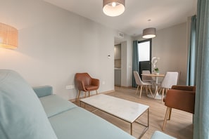 A modern living room with a sofa, a coffee table, and a dining area with chairs and a table.