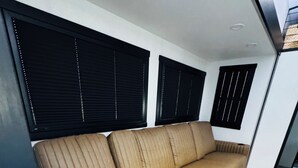 A modern interior with a beige sofa, black blinds, and a light-colored floor. - 2-bedroom recreational vehicle in lovely Exeter with AC (Exeter)