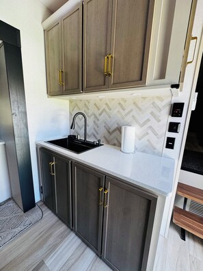 A compact kitchen with a sink, countertop, and cabinets. - 2-bedroom recreational vehicle in lovely Exeter with AC (Exeter)