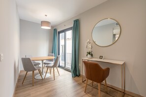 A modern dining area with a round table and chairs, a console table with a mirror, and a potted orchid. - A1 Apartment with Cathedral Views – Historic Center of Seville & Pool (Seville)