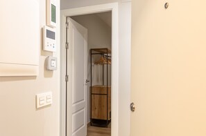 A hallway with a white door, a coat rack, and a thermostat on the wall. - A1 Apartment with Cathedral Views – Historic Center of Seville & Pool (Seville)