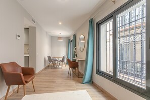 A modern interior with a dining area, a sofa, and a large window with a view. - A1 Apartment with Cathedral Views – City Center & Pool (Seville)