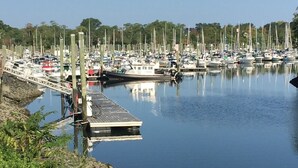 A marina with boats docked, a wooden dock, and a rocky shoreline.