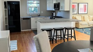A modern kitchen with white cabinets, a central island, and a dining area with a table and chairs.