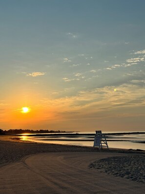 A beach scene with a lifeguard tower and a sunset.