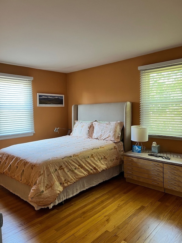 A bedroom with a bed, bedside table, lamp, and a framed picture on the wall.