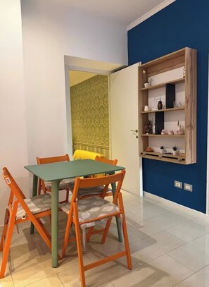 Comedor con mesa, sillas, pared azul y estantería de madera.
