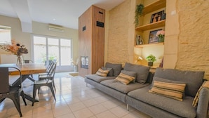 Uma sala de estar moderna com sofá, mesa de jantar, cadeiras e uma parede de destaque em pedra.