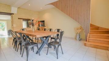 A dining area with a wooden table and metal chairs, a staircase, and a decorative vase with flowers.