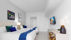 Et moderne hotelværelse med seng, sengebord, lampe og billedkunst på væggene.