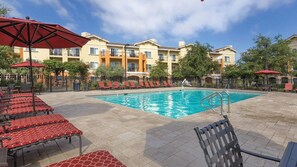 A swimming pool with lounge chairs and umbrellas, surrounded by a building with balconies. - Sip, Savor & Stay in Style — A Wine Country Escape- Wyndham Vino Bello- 1 Bd. (Napa)