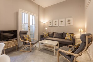 A living room with a sofa, two armchairs, a coffee table, a TV, and a floor lamp. - City Centre Apartment with Balcony, Elevator and WiFi (Seville)