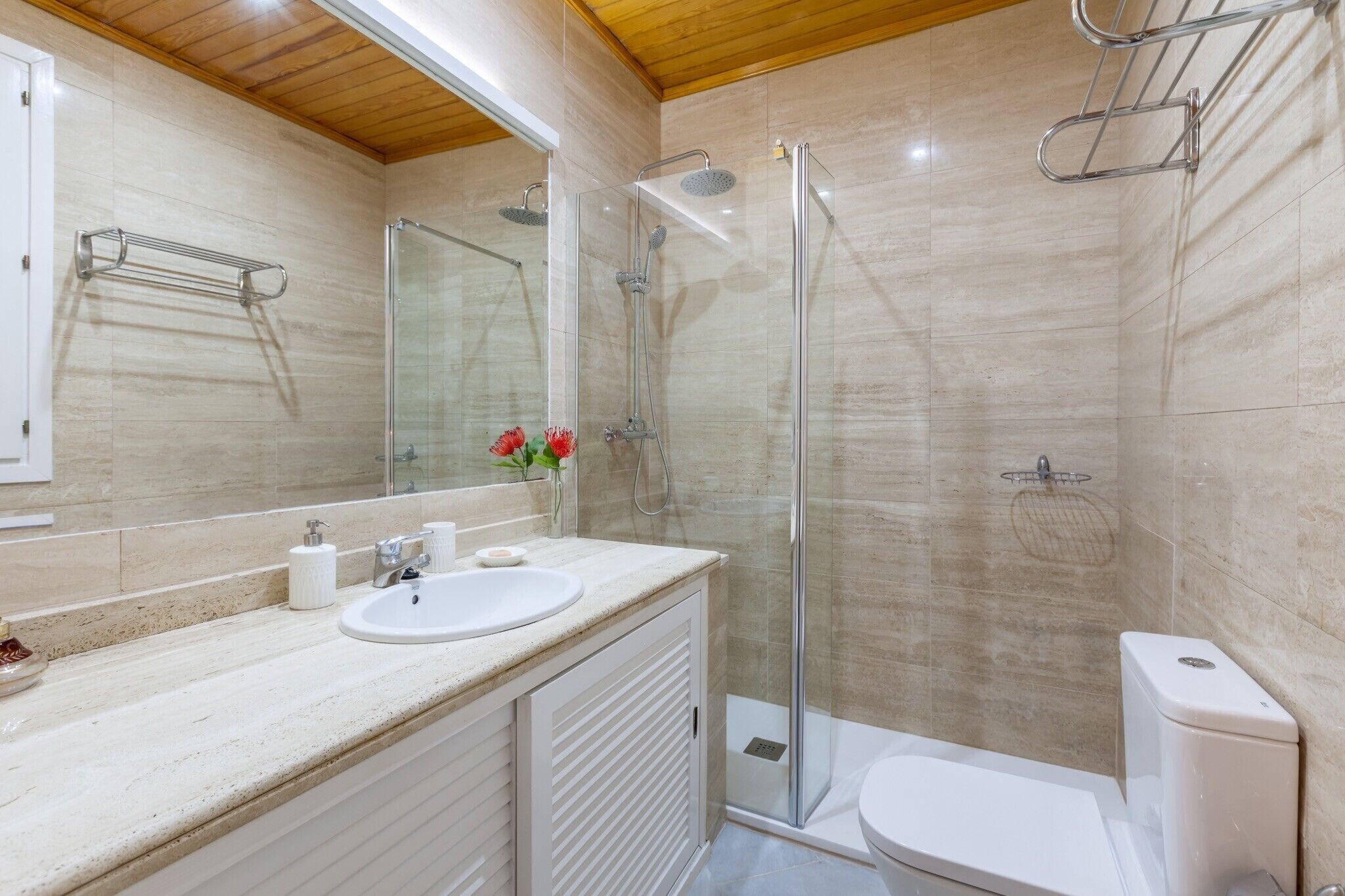 A modern bathroom with a glass shower enclosure, a white sink, and a toilet.