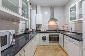 A modern kitchen with white cabinets, a built-in oven, a washing machine, and a microwave. - City Centre Apartment with Balcony, Elevator and WiFi (Seville)
